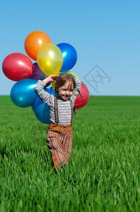 天空气球带着气球走在春田里的快乐女孩背景