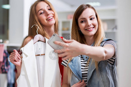 两个微笑的女孩在服装店买东图片
