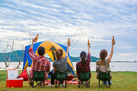 一群男人和女人享受露营野餐和在湖边的烧烤图片