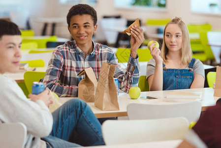 高中学生在食堂吃午餐时聊天的多种族多民族群图片