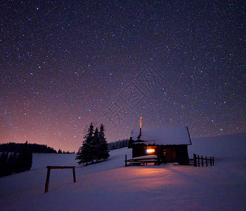 木屋窗外有一盏灯冬天的夜景图片