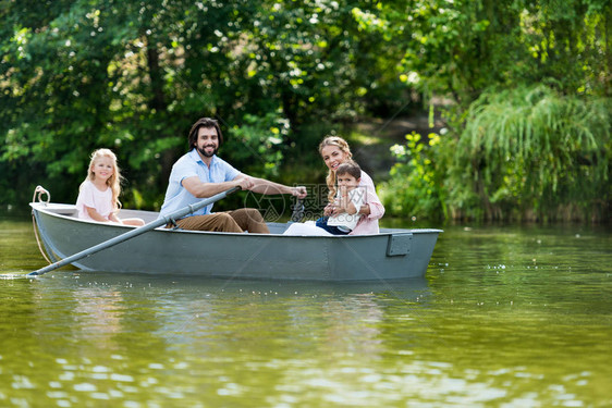 快乐的年轻家庭在公园河边的船上共渡时图片