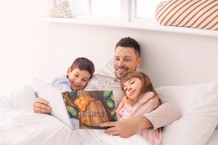 父亲和他的小孩在家看睡前故事图片