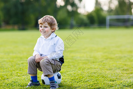 有趣的4岁小男孩在户外足球场上踢足球后休息带小孩的积极休图片
