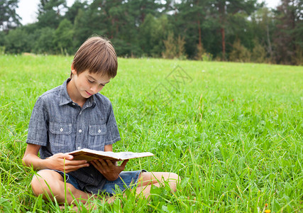 坐在草地上看书的男孩在图片