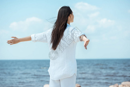 站在海边张开双臂站立的女人的后视图图片