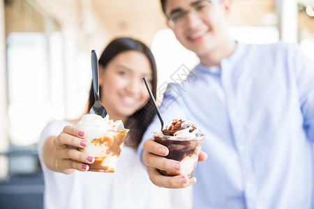 在商场里展示冰淇淋杯的散焦少年夫妇图片