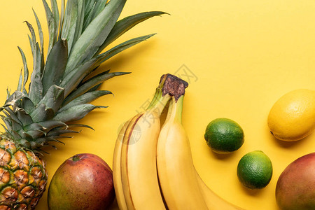 整个成熟香蕉菠萝柑橘水果和黄底芒果的顶部图片