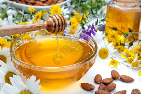 碗里的新鲜蜂蜜蜂蜜棒和鲜花背景图片