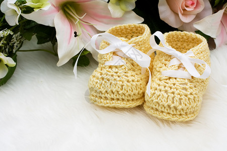 白色背景上有花朵的黄色婴儿短靴图片