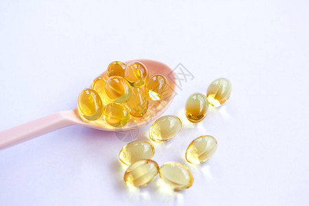 白色背景的Omega3鱼肝油囊大金半透明药片小勺子图片