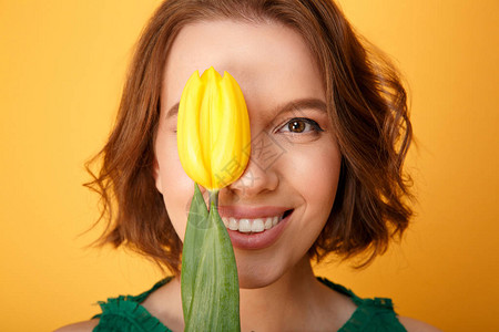 眼罩着微笑的女士用黄色的郁金香遮住眼睛在图片