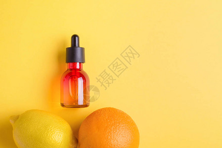 柠檬海报玻璃瓶和黄色背景上的橙色含有维生素C的有机生物化妆品极简主背景