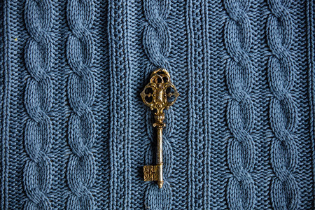 蓝色针织背景上的一把金钥匙背景图片
