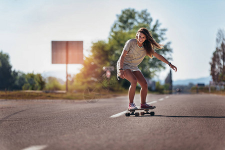 女生在道路上玩滑板图片