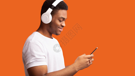 享受音乐吧笑的Afro家伙用耳机橙色工作室背图片