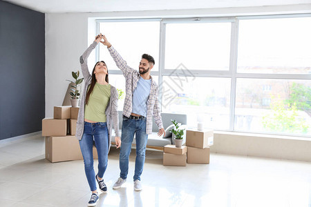年轻夫妇在他们的新房子里跳舞背景图片