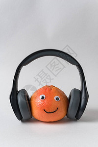 橙色笑脸与白色背景上的耳机有眼睛和微笑的水果有滑背景图片