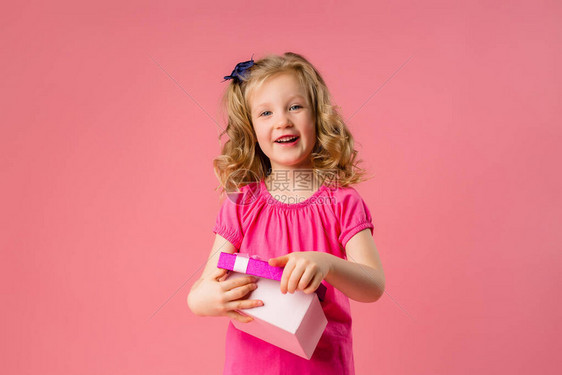 穿粉红色T恤的金发小美女打开礼物盒粉色背景复制空间图片并放置您的文本或广告儿童情感概念Phi图片