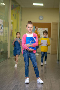 第一个去漂亮的女学生站在学校走廊里跑图片