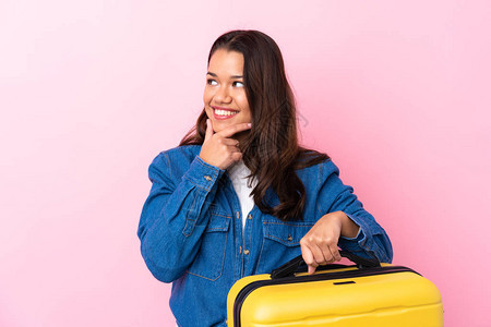 带着手提箱的哥伦比亚妇女与孤立的粉红背景相隔绝思考一个想法图片