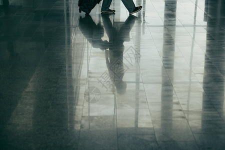 出发前在机场休息室行走的旅行人员腿和行李的图片