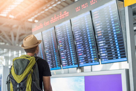 在机场看航班时刻表的旅行者背景图片