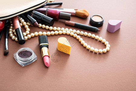 用专业配件组成化妆包棕色背景下金色化妆袋中的口红和刷图片