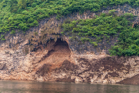 关闭棕色岩石悬崖水边的洞穴图片