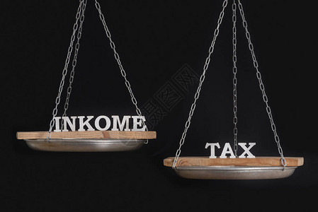 以单词收入和税收来缩放平衡概念黑背景的图片