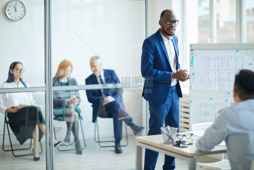成功的非洲裔美国商人在办公室会议期间展示设计项目时站在白板旁的肖图片