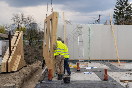 从复合sip面板建造新的现代模块化房屋的过程两名身着特殊防护服的工人在节能物业建筑背景图片