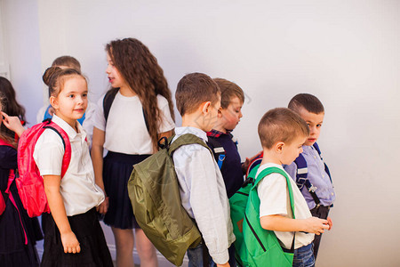 一群快乐的小学生在学校学校走廊里穿着制服背图片