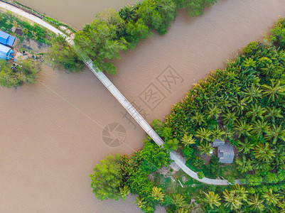 越南部本特雷湄公河三角洲地区泥水运河上的空中俯视桥热带岛屿郁葱的绿色图片