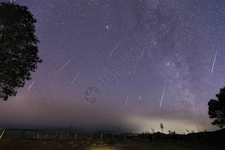 双子座流星雨和山上的银河夜空中的双子座流星图片