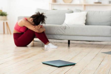 减肥失败抑郁的黑人妇女在称体重体重增加在家节食时不减掉多余的公斤后坐在体重秤旁哭泣选择图片
