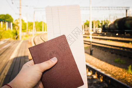 一只手拿着一张火车票和一本护照图片