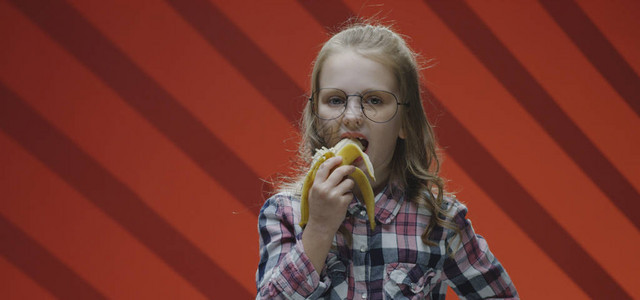 一个女孩吃香蕉然后向照相机抱图片