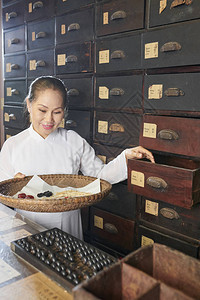 在古老传统药店的抽屉中取出干草药根茎和吸食室的微笑图片