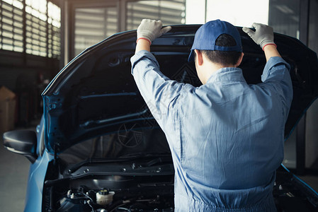 汽车修理工在汽车修理厂车库按客户索赔单打开汽车罩图片