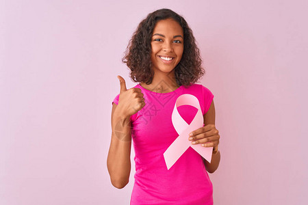 方向手势年轻的巴西女人拿着癌症丝带站在孤立的粉红色背景上背景