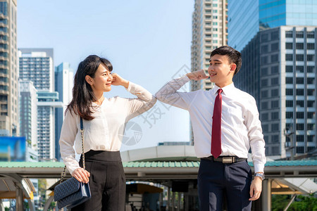 肘部肿块是避免冠状传播的新型问候语两个亚洲商业朋友在办公楼前见面他们没有用或握手打招呼背景图片