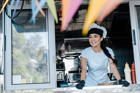 穿着帽子和厨师制服的快乐的亚洲女在食图片