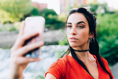 户外年轻妇女使用智能手机采取自我青年文化虚荣图片