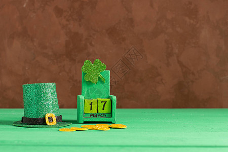 日期为3月17日的历绿色背景上的妖精帽子和三叶草圣帕特里克节庆祝概念复制空图片