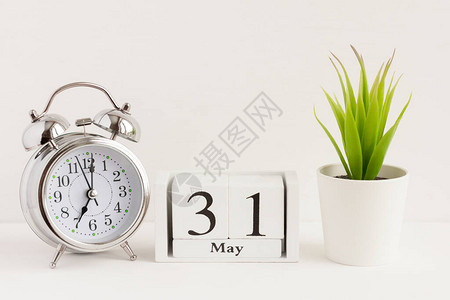 5月31日在闹钟和花旁边的木制日历上春季月份的一天图片