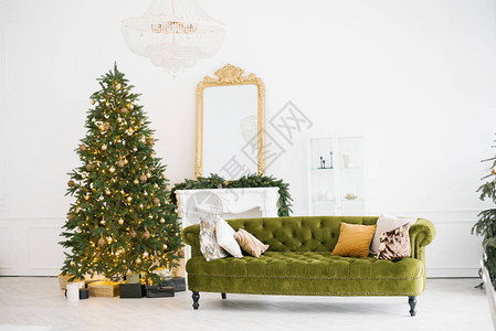 以古老风格绿色沙发壁炉圣诞树以及玩具和灯光装饰的圣诞装饰品图片