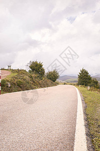 绿色田地与秋云下之间的风山道路前往最美的公路之旅图片