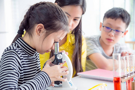 年轻女学生在科学课堂上看显微镜图片