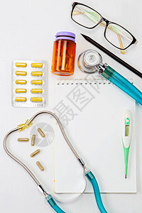 听诊器温度计药丸笔记板和眼镜放在医生桌或护士桌上图片